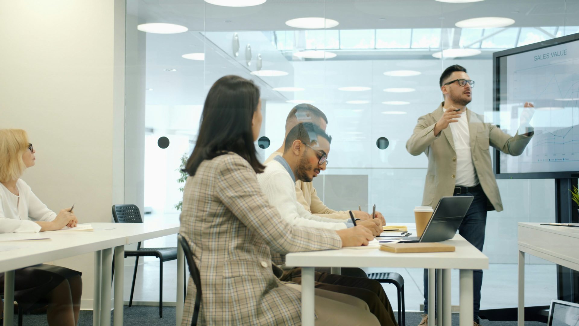 Un homme fait une présentation à ses collègues dans une salle de réunion de bureau moderne.
