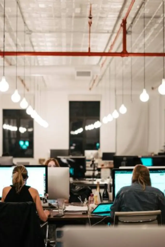 Quatre professionnels dans un espace de réunion de bureau moderne.