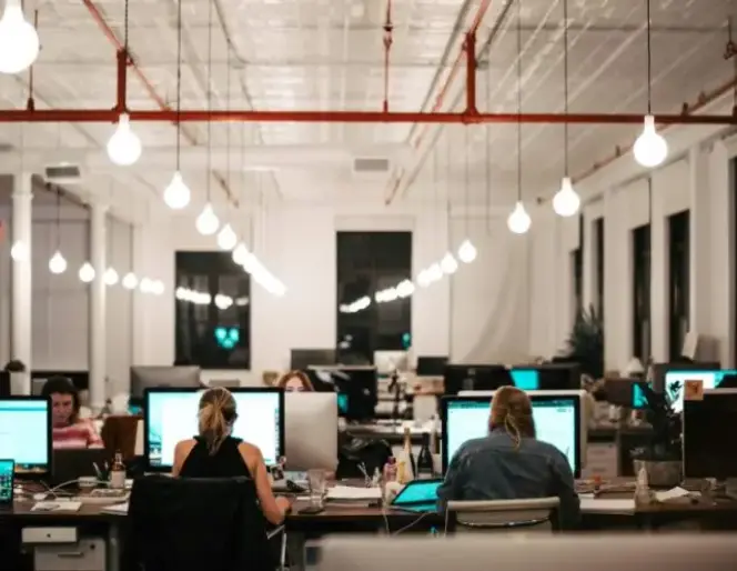 Quatre professionnels dans un espace de réunion de bureau moderne.